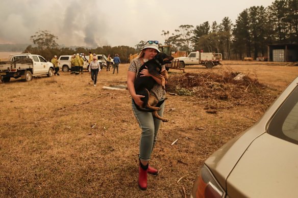 Tiana Hockey evacuates her dog as the North Black Range bushfire threatens properties at Bombay.