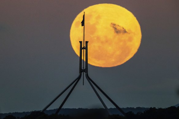 A supermoon is seen rising over Canberra with Parliament House in the foreground.