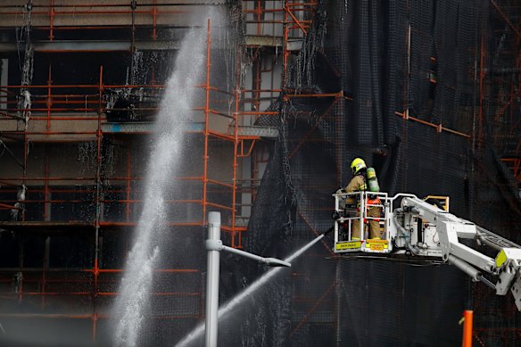 A firefighter pours water into the construction site after a fire broke out.