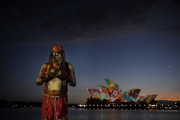 Koomurri performer Les Daniels in front of the projection of Pitjanjara artist Yadjidta David Miller's <i>Goanna Songline</i> on the Opera House sails on Australia Day. 