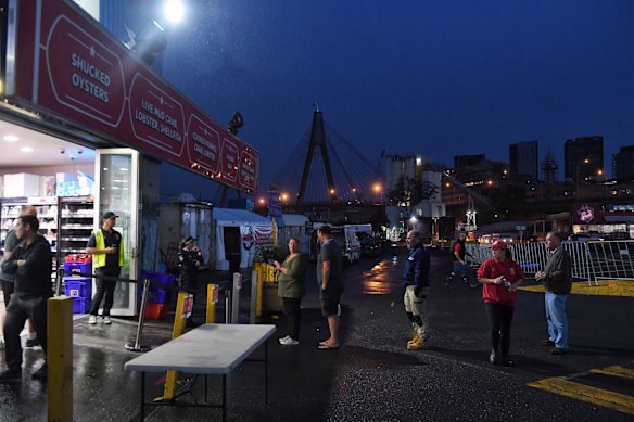 Good Friday shoppers have their temperatures tested and their hands sanitised before entering the Sydney Fish Market. 
