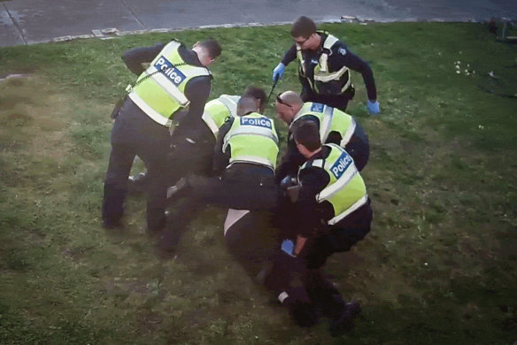 An image from CCTV showing police pinning pensioner John to the ground outside his home in Preston.