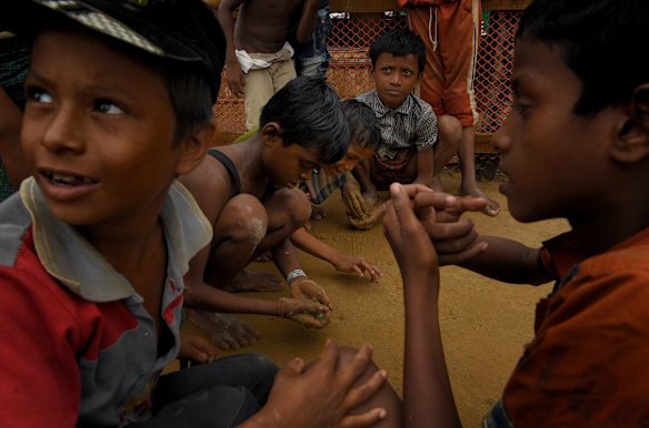 Rohingya children play in the mud with marbles in Kutupalong refugee camp after a monsoonal downpour. 