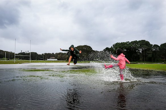 Ben and Louisa Roth make the most of a rainy day at a flooded sports field in Centennial Park, Sydney.