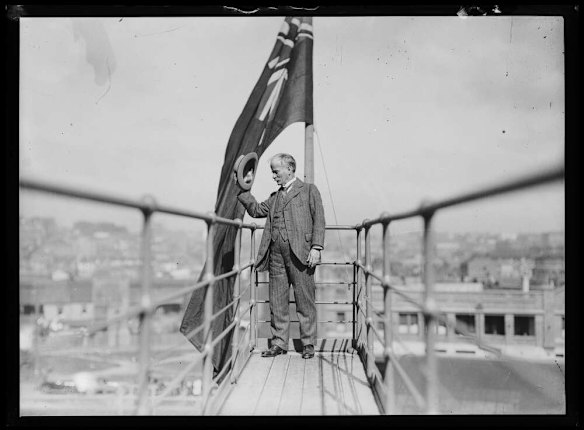 Engineer John Bradfield tipping his hat from a walkway on the newly constructed Sydney Harbour Bridge.