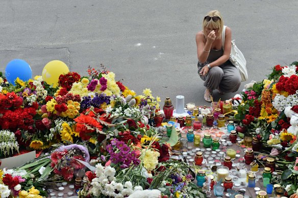 A woman crosses herself as people lay flowers and light candles in front of the Embassy of the Netherlands in Kiev on July 18, 2014, to commemorate passengers of Malaysian Airlines flight MH17 carrying 295 people from Amsterdam to Kuala Lumpur which crashed in eastern Ukraine.  Ukraine's prime minister said Friday that pro-Russian separatist rebels that Kiev believes shot down a Malaysian airliner with 298 people on board should face an international tribunal in The Hague.
