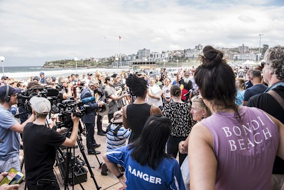 Crowds gather as NSW Police Minister David Elliott announces the NSW government would enforce restrictions on the number of people at beaches.