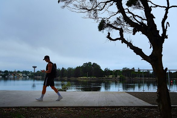 A man walks along a path near the waters edge of the Cooks River at Cahill Park in Wolli Creek in Sydney.
