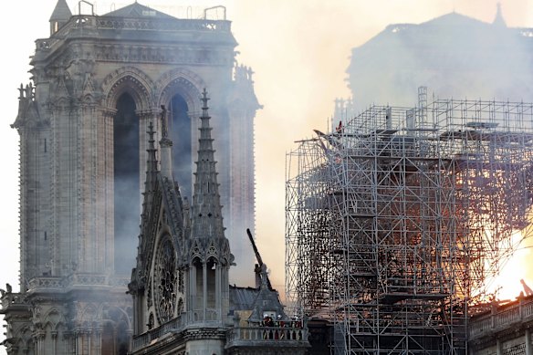Firefighters tackle the blaze as flames and smoke rise from Notre Dame cathedral as it burns in Paris.