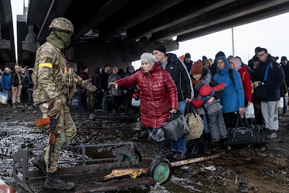 Residents of Irpin flee heavy fighting via a destroyed bridge as Russian forces entered the city.