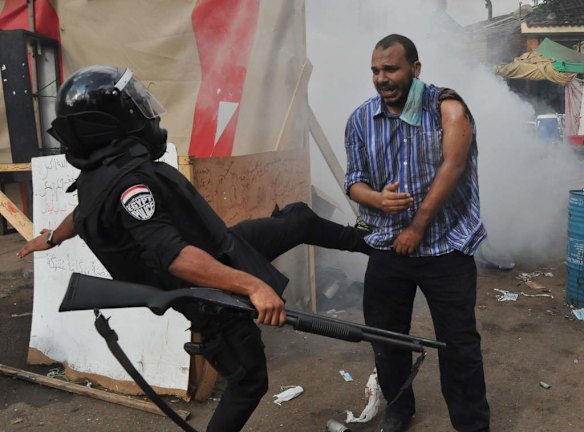 An Egyptian security force kicks a supporter of ousted Islamist President Mohammed Morsi as they clear a sit-in camp set up near Cairo University in Cairo's Giza district, Egypt.