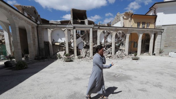 A nun talks on the phone as she walks in the courtyard of a damaged convent following an earthquake in Amatrice, central Italy. 