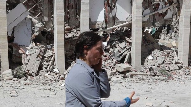 A nun talks on the phone as she walks in the courtyard of a damaged convent following an earthquake in Amatrice, central Italy. 