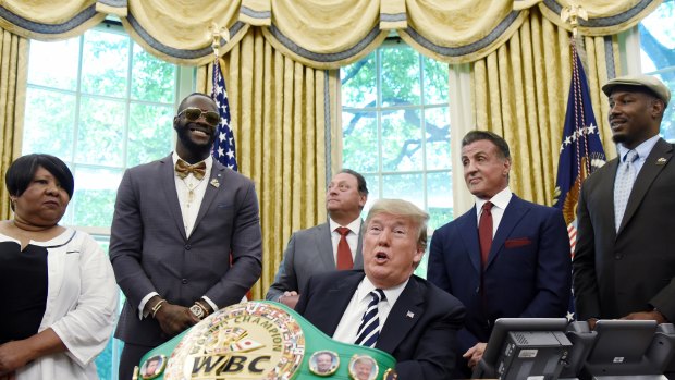 US President Donald Trump speaks after signing an executive order granting a posthumous pardon for Jack Johnson, the first black heavyweight boxing champion, as boxing champion Lenox Lewis, from left, and actor Sylvester Stallone attend in the Oval Office.