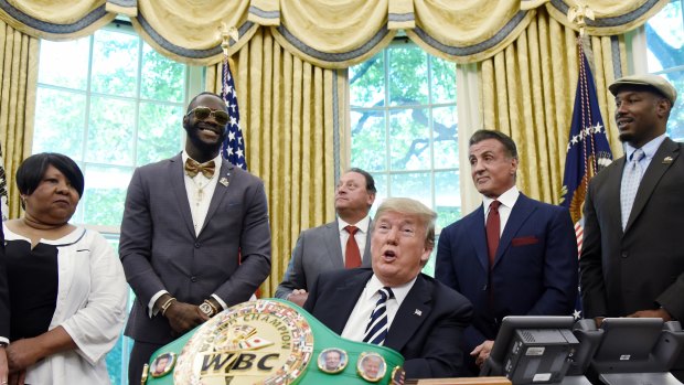 US President Donald Trump speaks after signing an executive order granting a posthumous pardon for Jack Johnson, the first black heavyweight boxing champion, as boxing champion Lenox Lewis, from left, and actor Sylvester Stallone attend in the Oval Office.