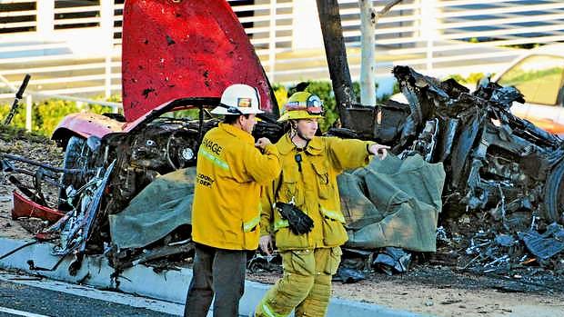 First responders gather evidence near the wreckage of a Porsche sports car.