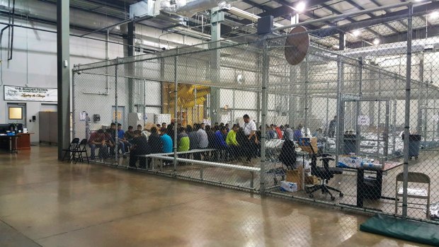 People taken into custody sit in one of the cages at a facility in McAllen, Texas. 