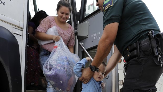 A transport officer helps immigrants Dilma Araceley Riveria Hernandez and her son, Anderson Alvarado, 2, get off the bus after they were processed and released by US Customs and Border Protection in McAllen, Texas.