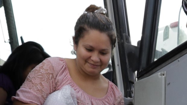 A transport officer helps immigrants Dilma Araceley Riveria Hernandez and her son, Anderson Alvarado, 2, get off the bus after they were processed and released by US Customs and Border Protection in McAllen, Texas.