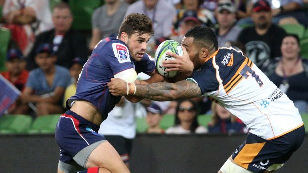 Tom English of the Rebels is tackled by Lolo Fakaosilea of the Brumbies.