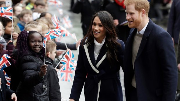 Prince Harry and his fiancee Meghan Markle are greeted by flag-waving school children in Birmingham.