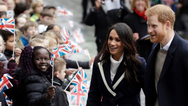 Prince Harry and his fiancee Meghan Markle are greeted by flag-waving school children in Birmingham.