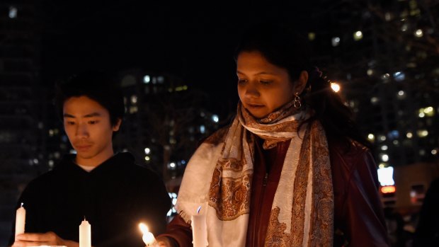 People light candles at a makeshift memorial to victims after a van mounted a footpath, crashing into pedestrians in Toronto in April.