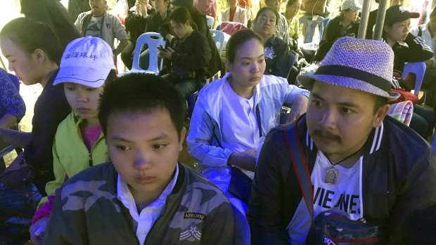 Songpol Kanthawong, 13, sits with his father Noppadon Kanthawong, right, in a tent outside the cave where his soccer team and coach are trapped.