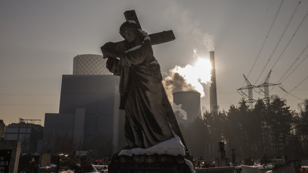 A statue, adorning a tomb, is seen at the cemetery of Bedzin, Poland, in the vicinity of the city's coal-fuelled power plant. 