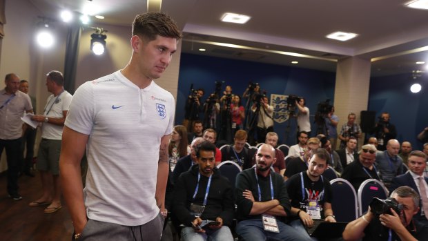 Talking tough: England's John Stones walks into a packed press conference ahead of England's quarter-final.