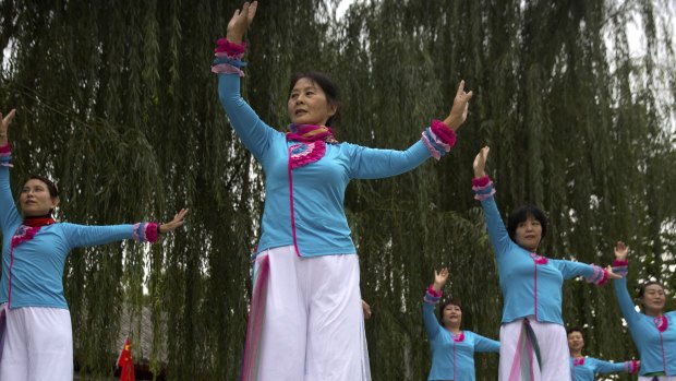 Women practice a dance routine outside residential community meeting during a media tour highlighting the Communist Party's efforts at the grassroots level in Beijing.
