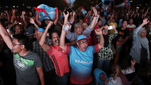 Opposition party supporters cheer and wave their party flags after Mahathir claimed victory.