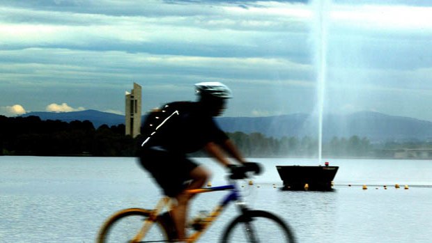 A cyclist riding on a bike track around Lake Burley Griffin in Canberra.