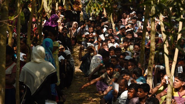 Rohingya refugees sit in a queue at a Red Cross distribution point in Cox’s Bazar, Bangladesh.