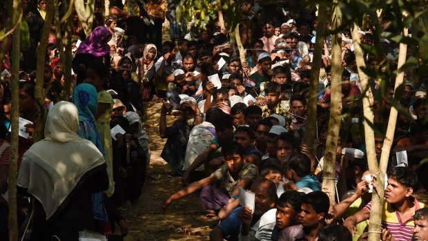 Rohingya refugees sit in a queue at a Red Cross distribution point in Cox’s Bazar, Bangladesh.