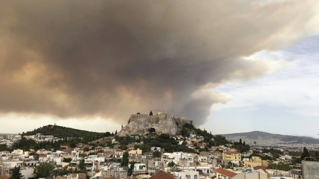 A pall of smoke turns large parts of the sky orange, with the ancient Acropolis hill at centre.