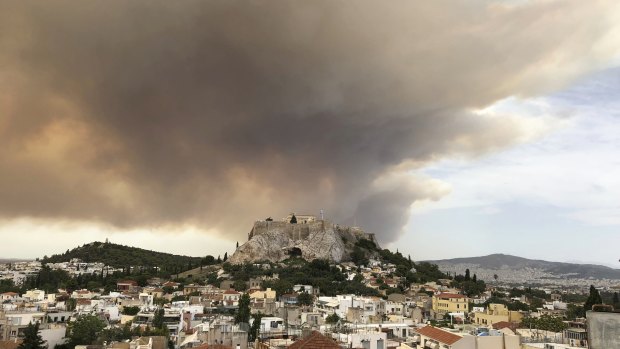 A pall of smoke turns large parts of the sky orange, with the ancient Acropolis hill at centre.