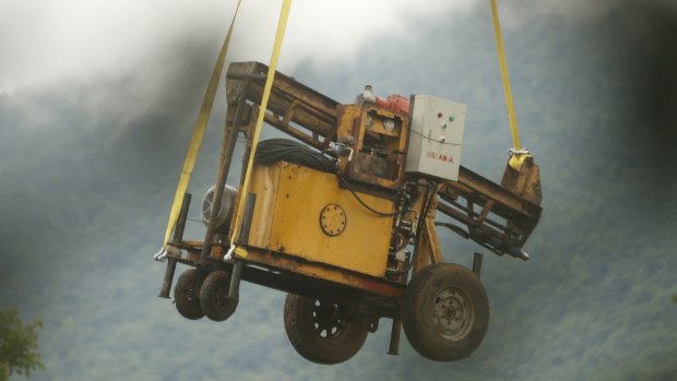 A military transport helicopter carries a drill machine to be used for the rescue.