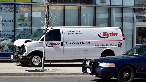 A van with a damaged front-end is shown on a sidewalk after the van mounted a sidewalk crashing into a number of pedestrians in Toronto.