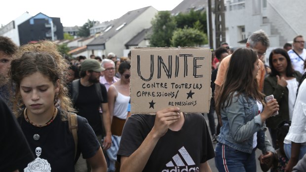 A man holds a poster reading "United against any oppression" during a silent march in Nantes, France.
