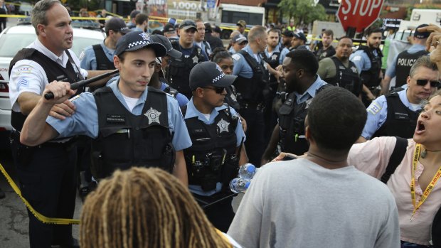 Members of the Chicago Police Department interact with an angry crowd at the scene of a police-involved shooting.