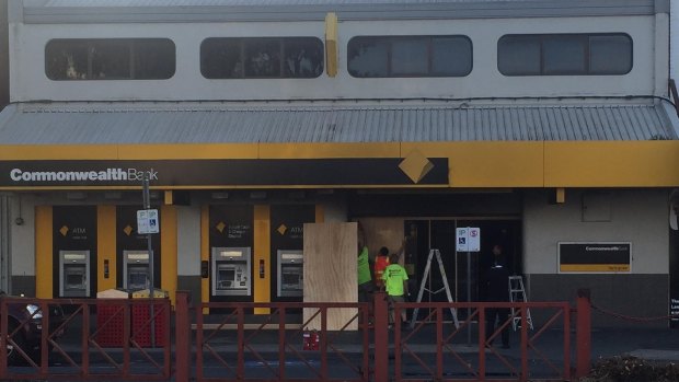 Workers boarding up the front entrance of the Commonwealth Bank on Springvale Rd after a man doused himself in what was believed to be petrol and ignited himself, seriously burning at least five others.