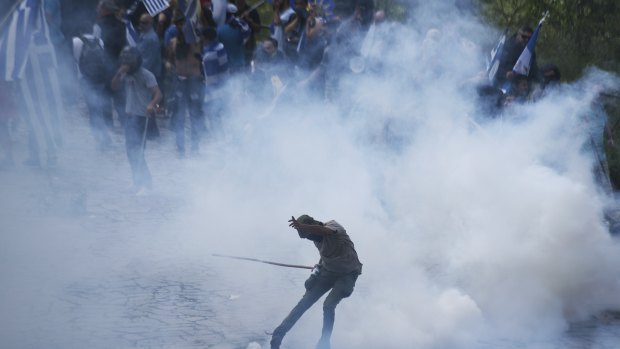 An opponent of the deal kicks a tear gas thrown by riot police during clashes at the village of Pisoderi, Prespes near the border with Macedonia in northern Greece, on Sunday.