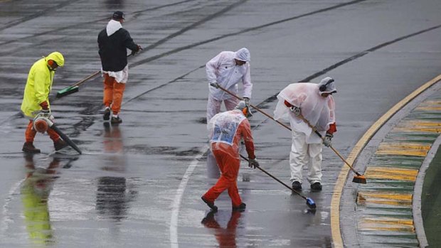 Marshals remove excess water from the track before the qualifying session.