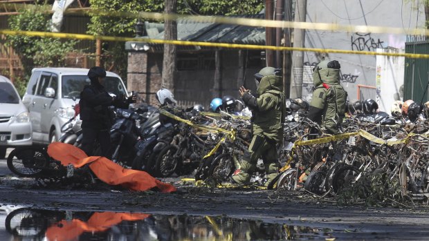 Members of police bomb squad inspect wreckage of motorcycles at the site where an explosion went off outside a church in Surabaya, East Java, Indonesia.