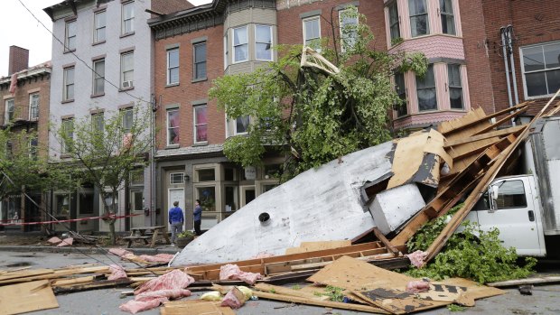 Men stand near buildings damaged by a storm in Newburgh, New York on Wednesday.