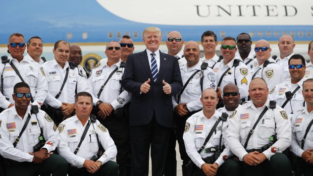 Not quite thumbs up yet: Donald Trump is enthusiastic about North Korea. Here he poses with police officers before boarding Air Force One during his departure from Palm Beach .