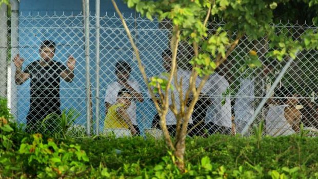 Asylum seekers stand and sit behind the wire of the Manus Island detention centre in Papua New Guinea.