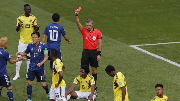 Take a walk: Referee Damir Skomina shows a red card to Colombia's Carlos Sanchez, who is sitting on the ground.
