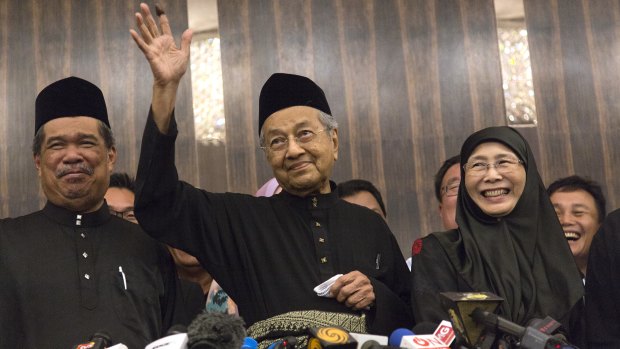 Newly-elected Mahathir Mohamad, centre, waves next to Deputy Prime Minister Wan Azizah, right, in Kuala Lumpur on Friday.